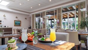 A restaurant with tables, chairs, and a large window with a view of greenery. - Plaza Camelinas Hotel (Querétaro)