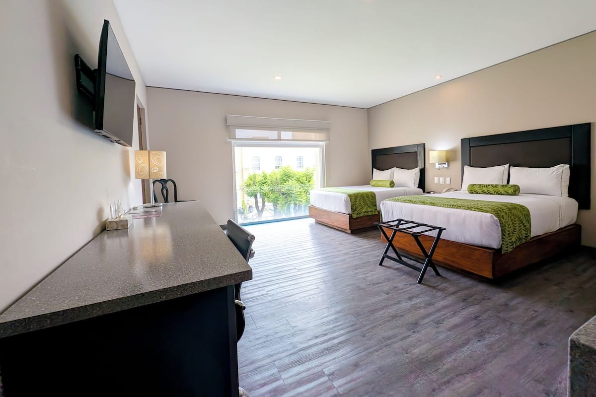 A modern hotel room with two beds, a desk, and a TV.