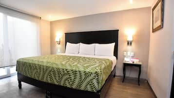 Un letto rifatto con cura, una coperta a motivi, un comodino con una lampada e un quadro incorniciato al muro.
