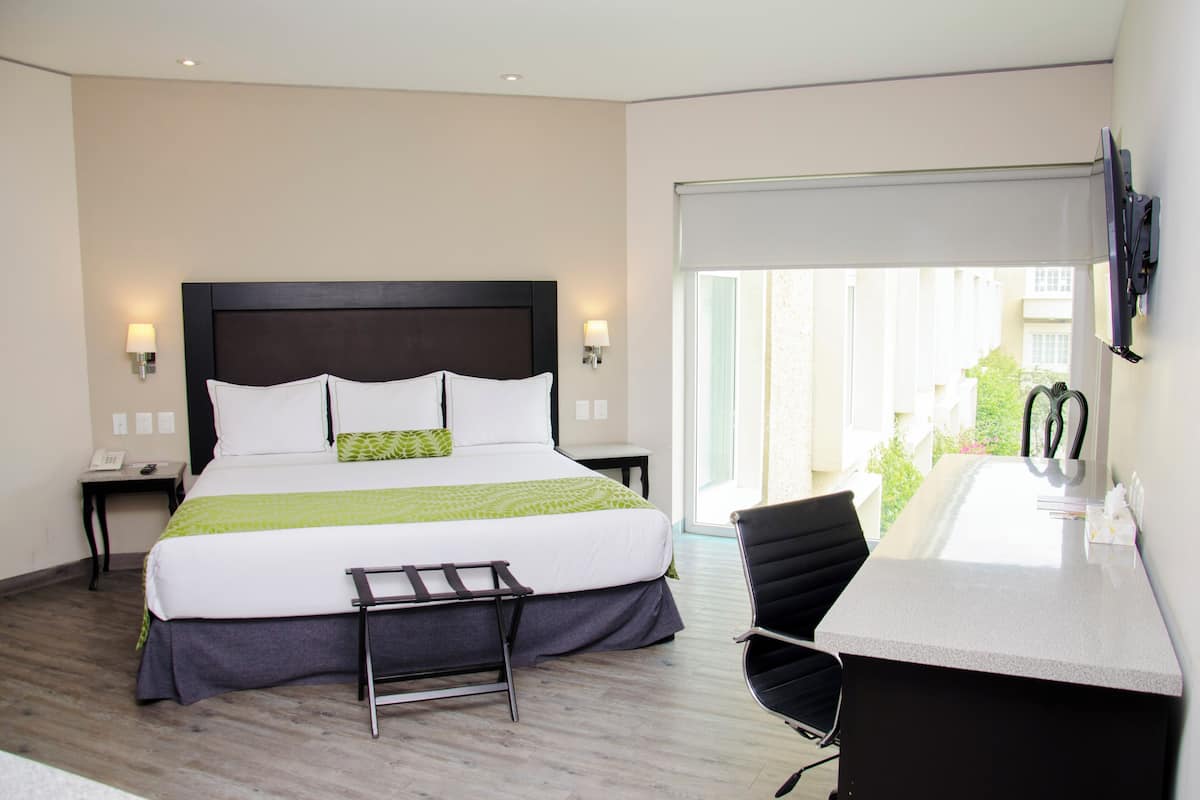 A hotel room with a bed, bedside tables, a desk, and a chair.