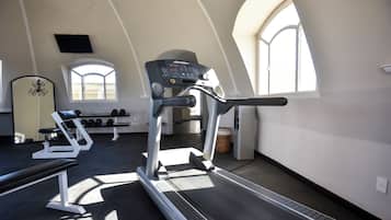 A gym with treadmills, weight benches, and dumbbells.