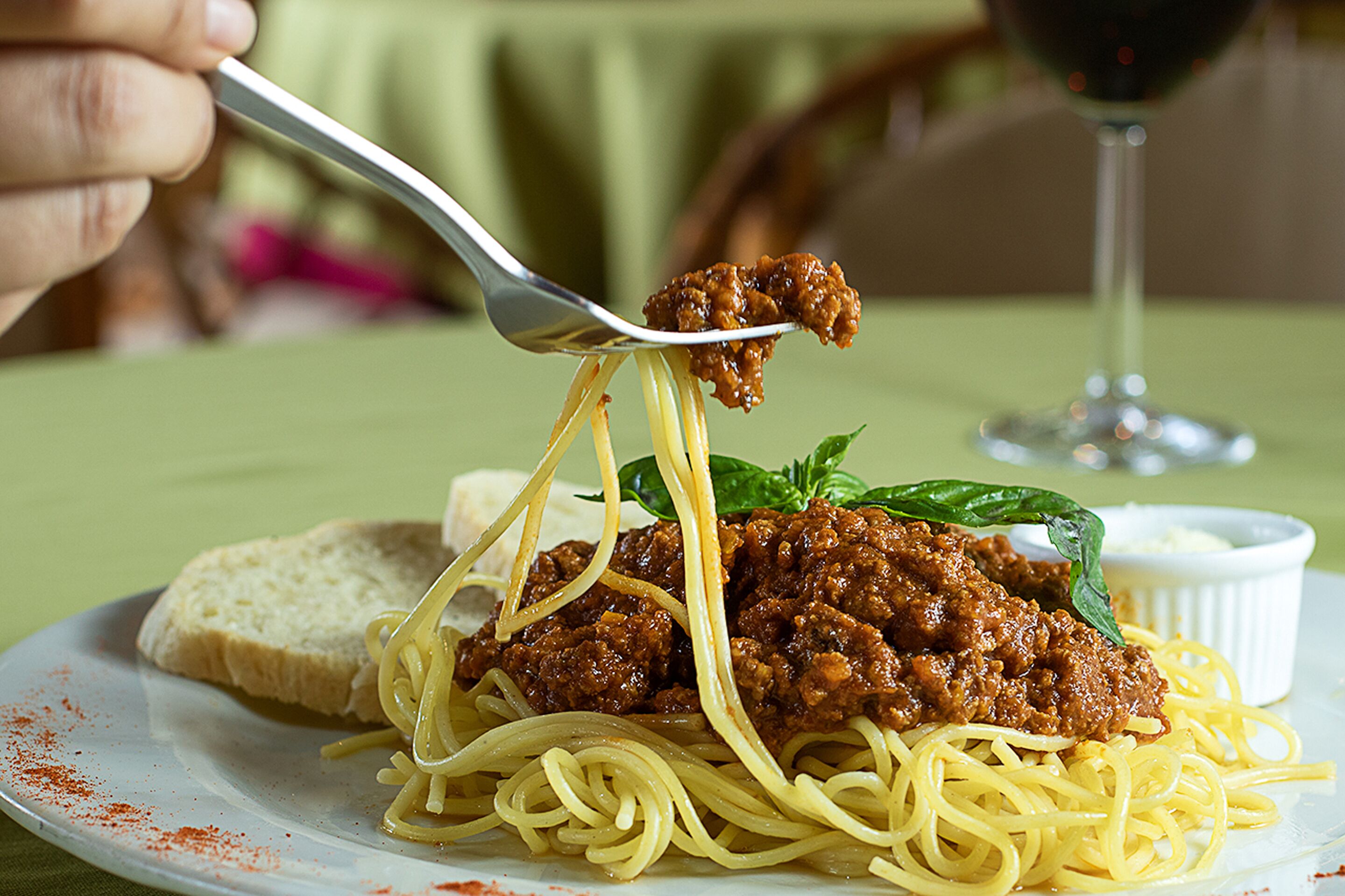 A plate of spaghetti with meat sauce and a fork lifting a portion.