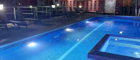 Une piscine dotée d’une terrasse carrelée, de chaises longues et de parasols.
