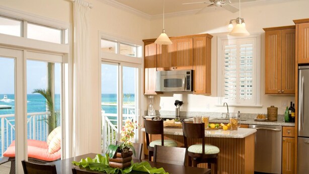 A modern kitchen with wooden cabinets, a central island, and a view of the ocean. - Cape Eleuthera Resort & Marina (Freetown)