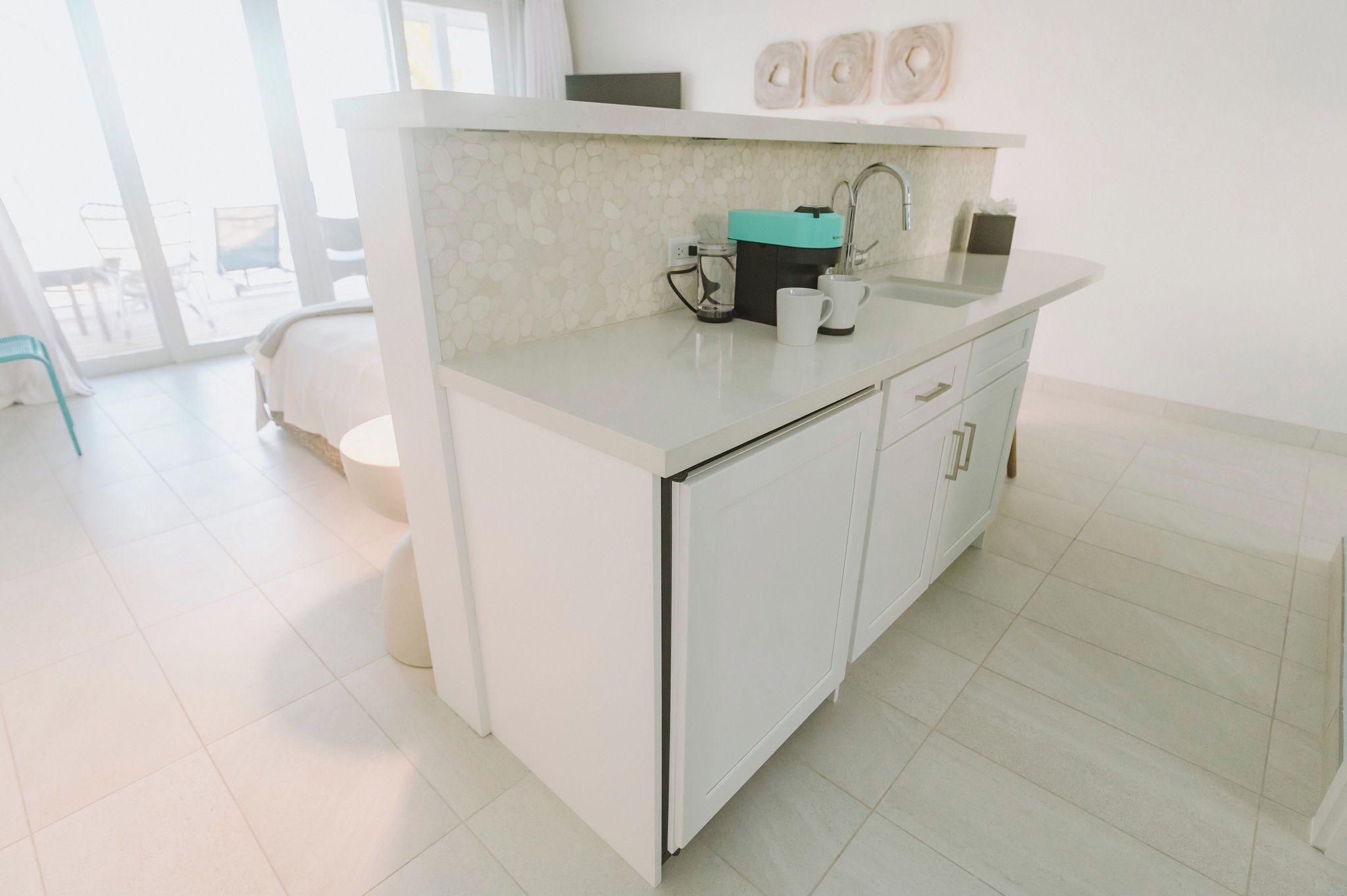 A modern kitchen with a white countertop, a sink, and a coffee maker.