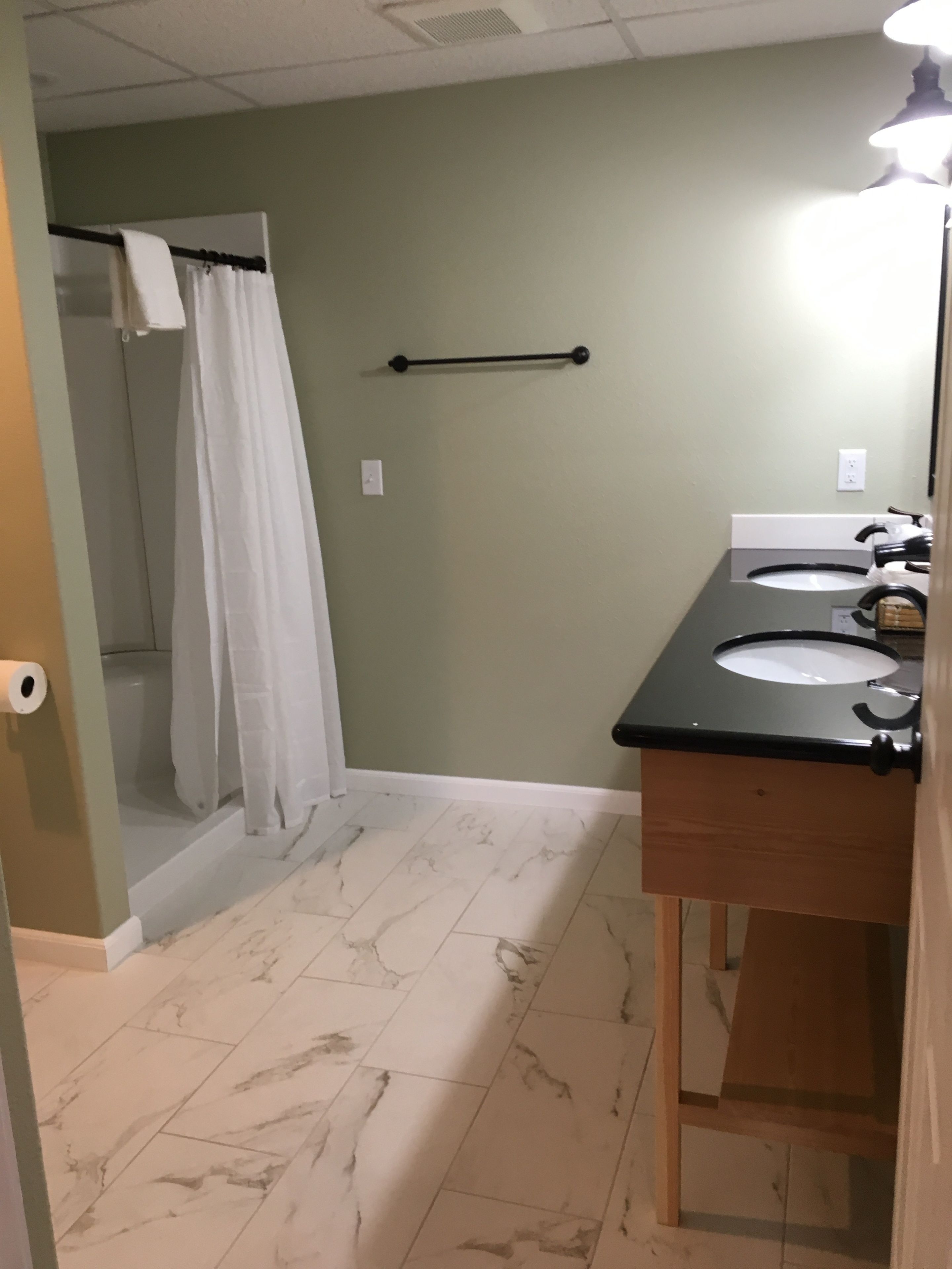 A bathroom with two sinks, a shower, and a towel rack.