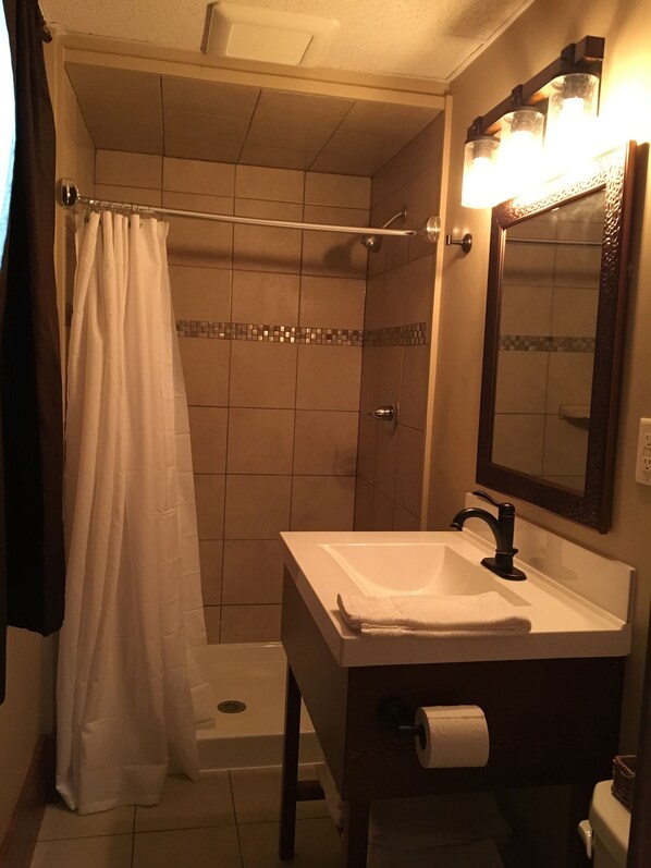 A bathroom with a shower, a sink, a mirror, and a towel rack. - Glacier Basecamp Lodge (Columbia Falls)