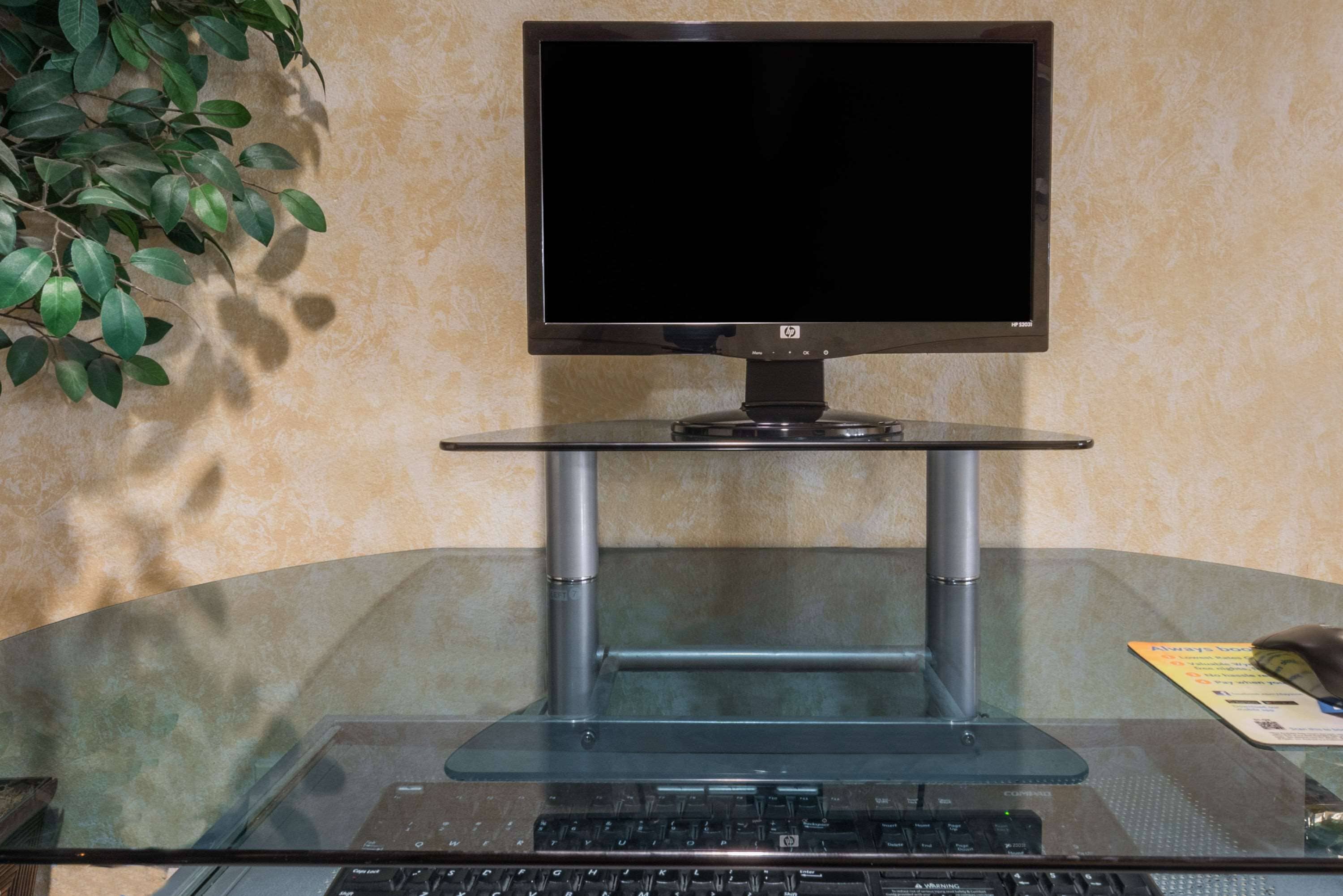 Un ordinateur installé sur une table en verre, avec un écran, un clavier et une carte posée sur la table.
