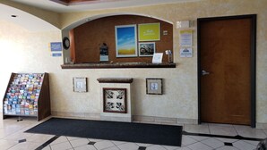 Un'area reception con una scrivania in legno, opere d'arte incorniciate, un calendario e il cartello di Days Inn.