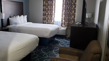 A hotel room with two beds, a TV, a chair, and a patterned carpet.
