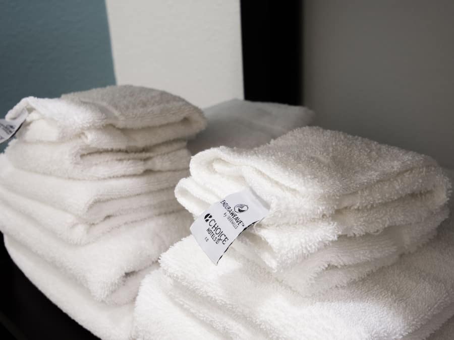 Montones de toallas blancas con etiquetas, probablemente en un hotel.