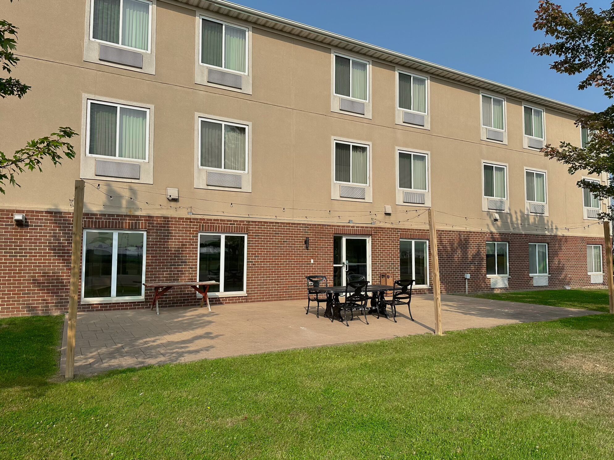 A multi-story building with a brick facade, large windows, and a patio area with outdoor seating.