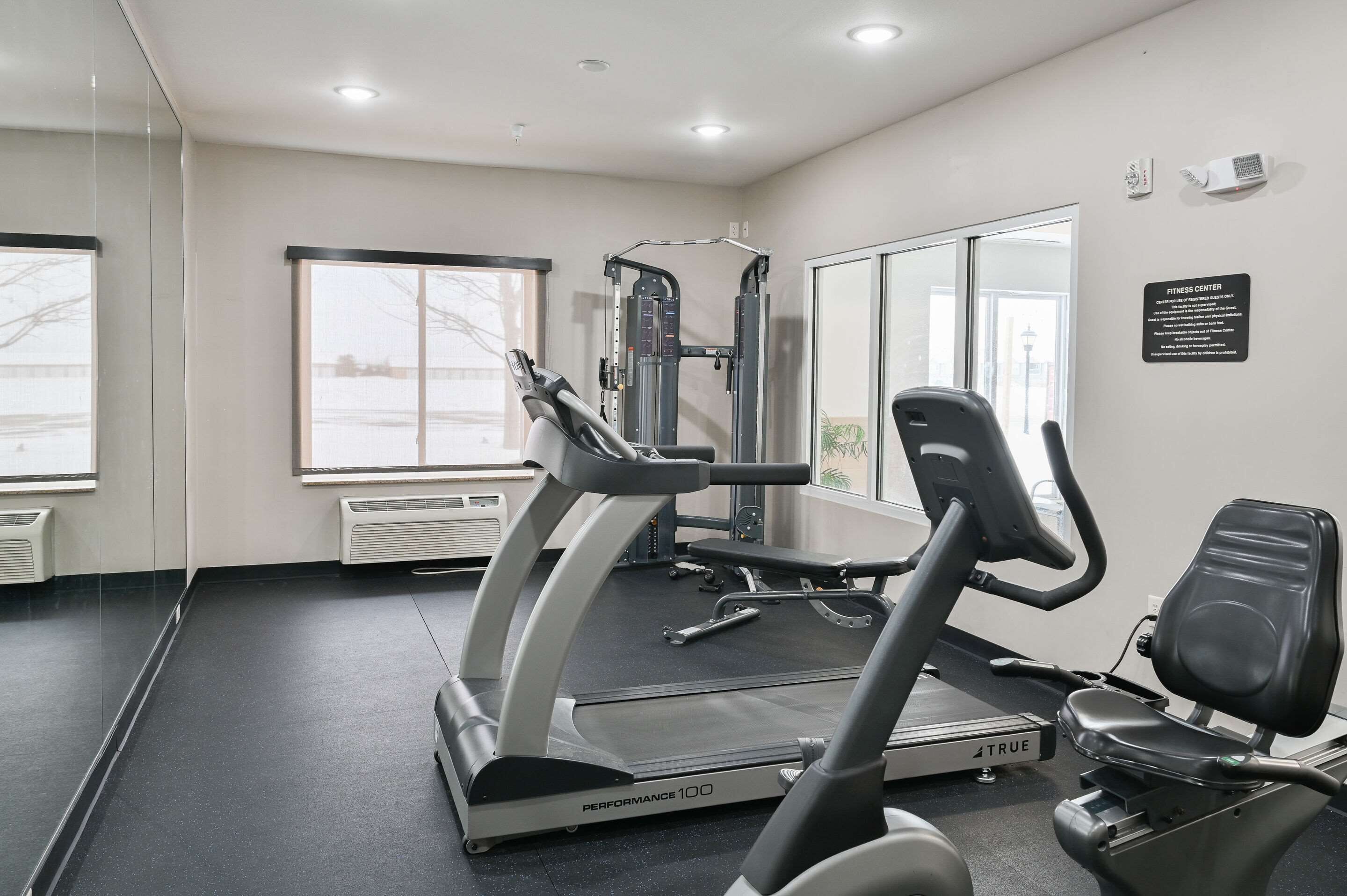 A fitness center with a treadmill, weight machine, and exercise chair.