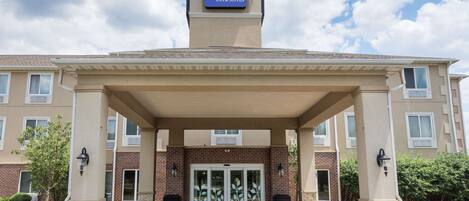 A Sleep Inn & Suites building with a covered entrance, brick facade, and a sign above the entrance.
