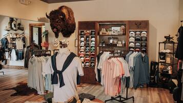 A clothing store with racks of clothes, a mannequin, and a display of hats.