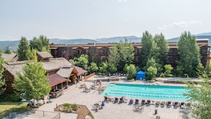 A resort with a swimming pool, outdoor seating, and a view of mountains. - The Lodge at Bronze Buffalo Ranch (Victor)