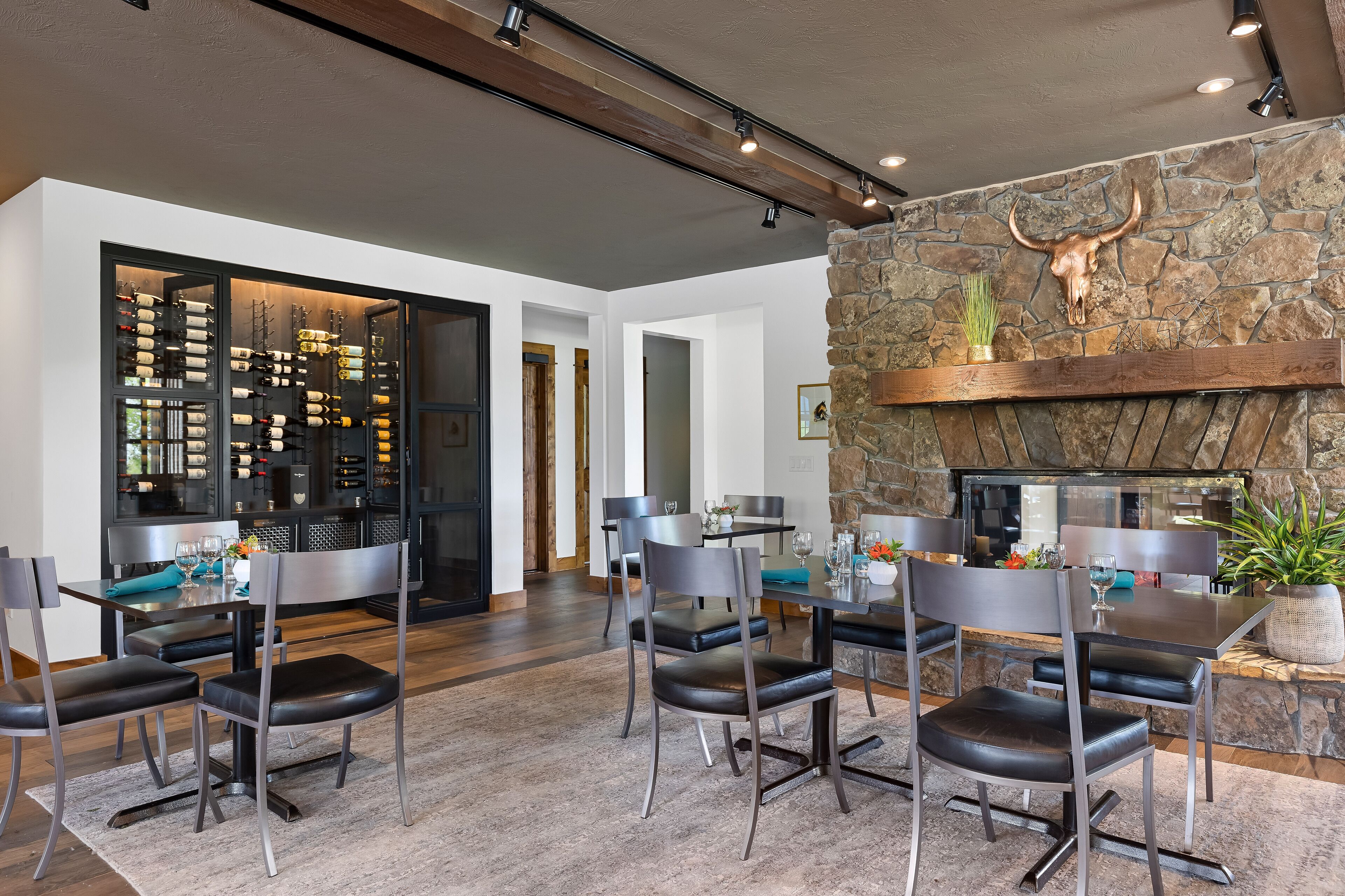 A modern dining area with a stone fireplace, a wine rack, and a dining table set for six.