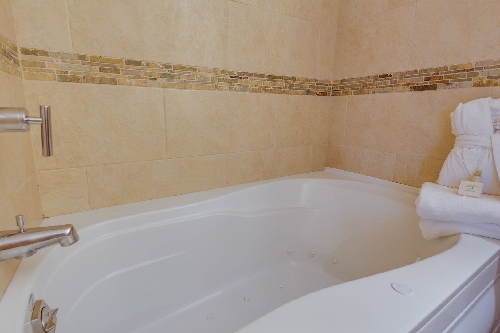 A bathroom with a bathtub, a towel rack, and a bottle of shampoo.