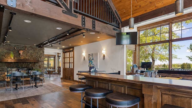 A spacious kitchen with a wooden bar area, stone wall, and large windows. - The Lodge at Bronze Buffalo Ranch (Victor)