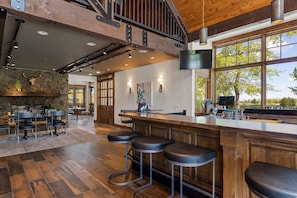 A spacious kitchen with a wooden bar area, stone wall, and large windows. - The Lodge at Bronze Buffalo Ranch (Victor)