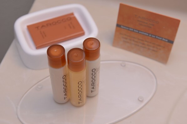 Three bottles of Tarocco on a white surface with a white container and a business card in the background. - Aspen Extended Stay Suites Kenai (Kenai)