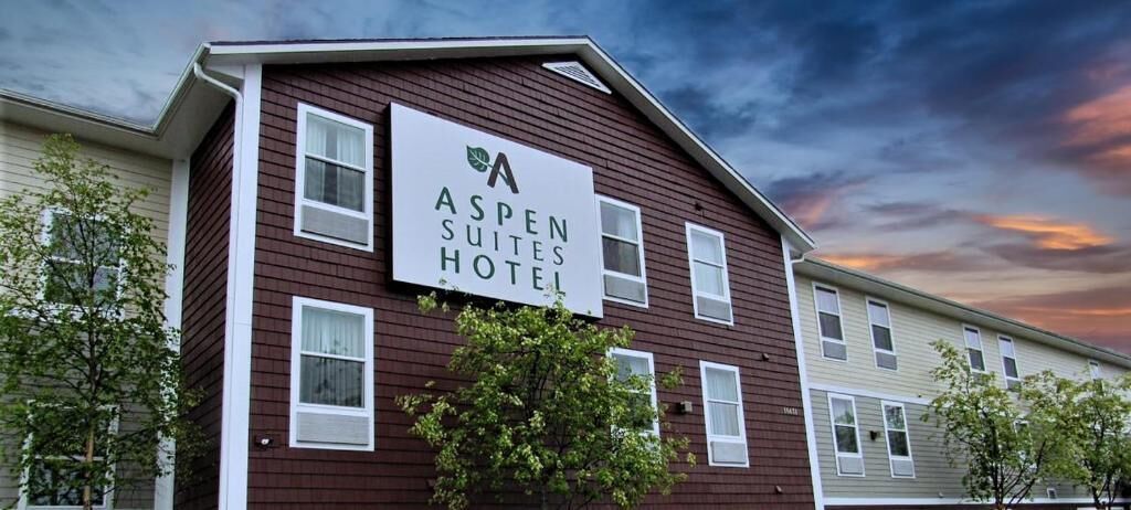 Un immeuble de deux étages avec une enseigne indiquant « Aspen Suites Hotel ».