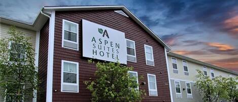 En tvåvåningsbyggnad med en skylt som visar att det är Aspen Suites Hotel.