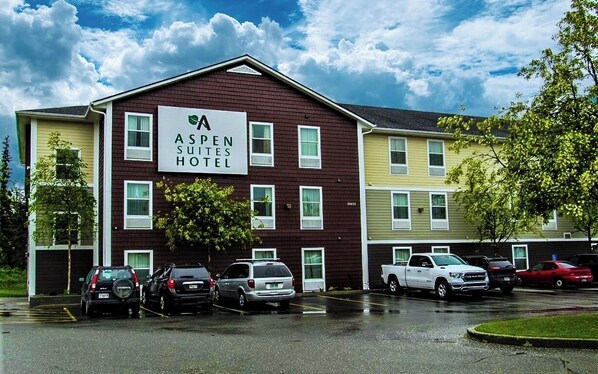 Aspen Suites Hotel with a parking lot and several cars parked in front.