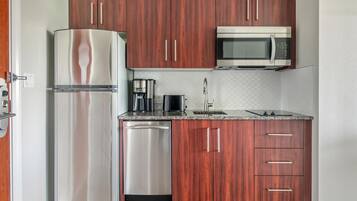 Una cocina funcional con electrodomésticos de acero inoxidable, armarios de madera y encimera de granito.