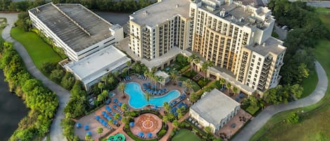 A high-rise hotel with a swimming pool, tennis courts, and a landscaped area.
