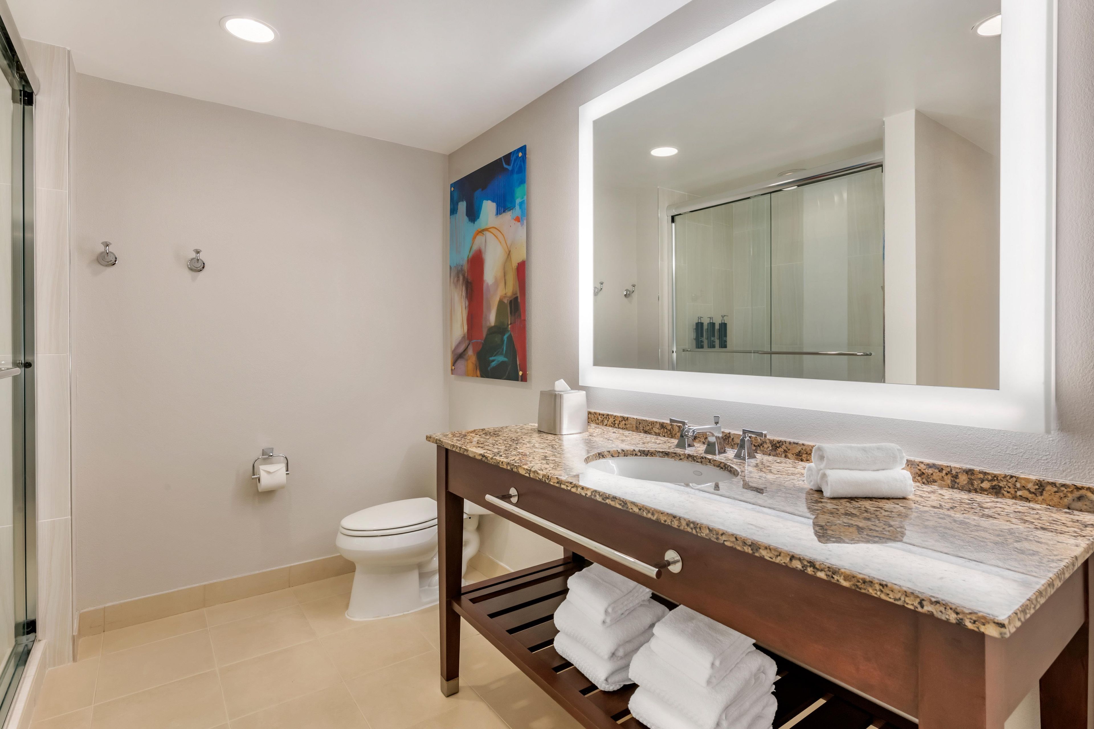 A modern bathroom with a large mirror, a sink, and a toilet.