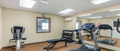 A gym with cardio equipment, weight machines, and a mirrored wall.