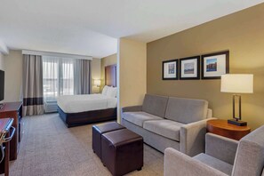 A hotel room with a bed, a sofa, a desk, and a TV.
