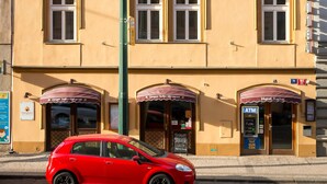 A multi-story building with a yellow facade, multiple windows, and two ground-level entrances with awnings. - Hotel Karlin (Prague)