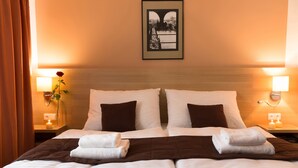 A hotel room with two beds, a framed picture on the wall, and bedside lamps. - Hotel Karlin (Prague)