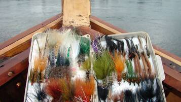 Un bote de madera con dos bandejas de señuelos de pesca.