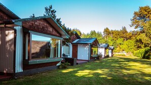 A row of cabins with large windows and a grassy yard. - Cabanas y Piscina Rucamalen (Puerto Varas)