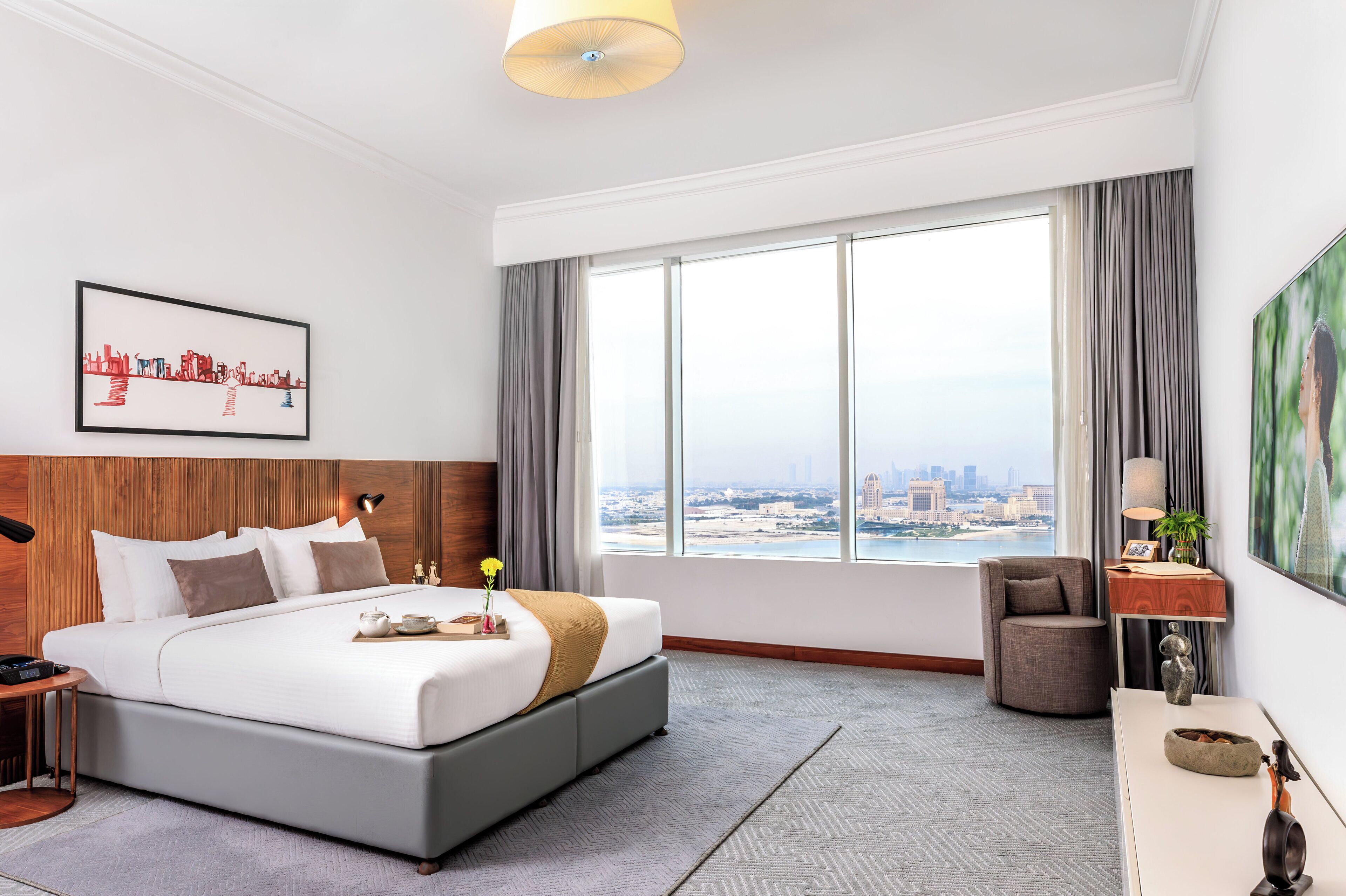 Une chambre d’hôtel moderne avec un grand lit, un bureau, une chaise et une vue sur la ville.
