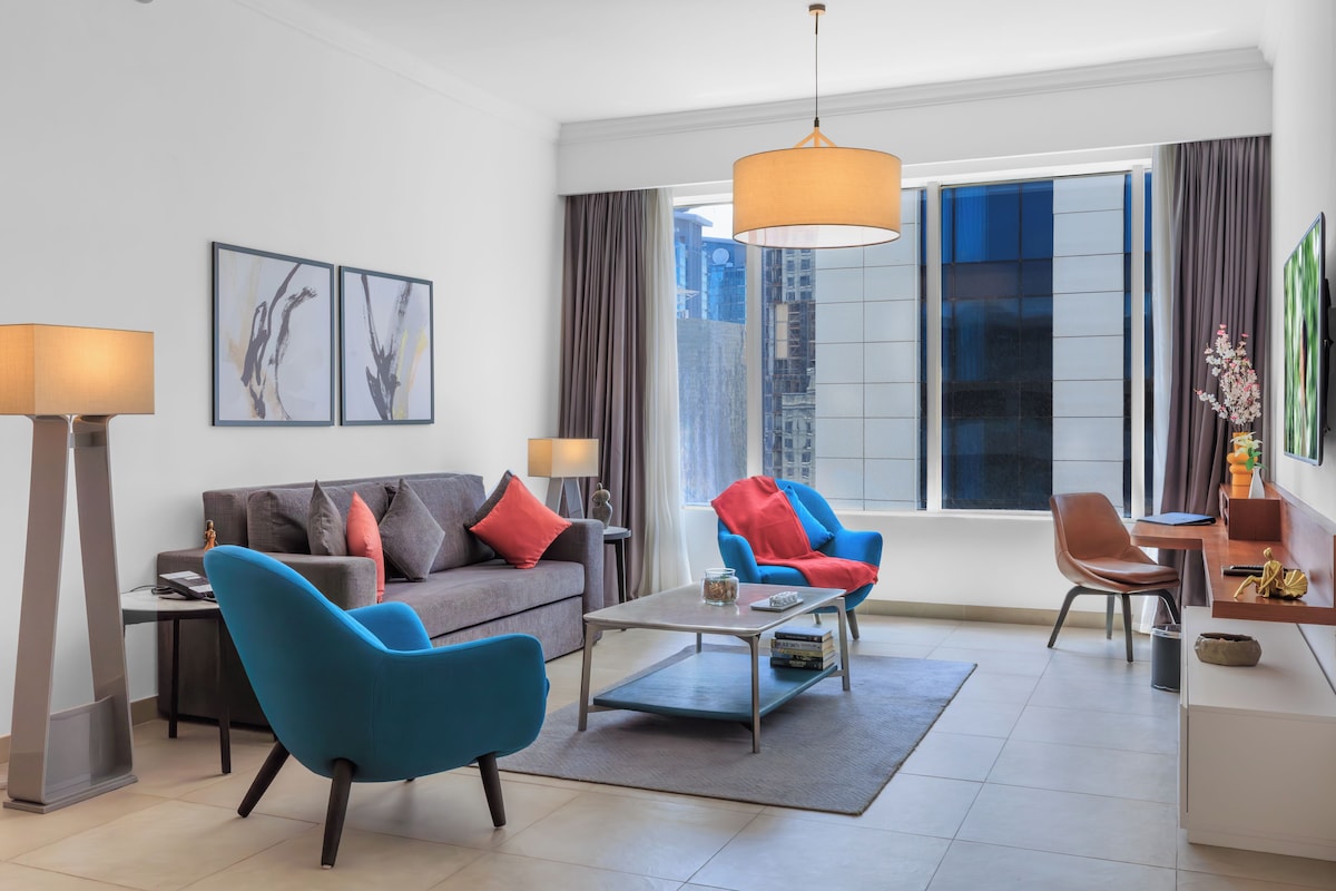 Una sala de estar moderna con un sofá, dos sillones, una mesa de centro y un comedor con mesa y sillas.