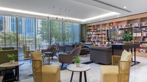 Una zona relax moderna con divani, poltrone e una libreria piena di libri.