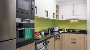 A modern kitchen with a built-in oven, a washing machine, and a coffee maker.
