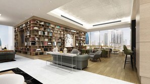Un soggiorno moderno con una grande libreria, un divano, un'area pranzo e vista sulla città attraverso ampie finestre.
