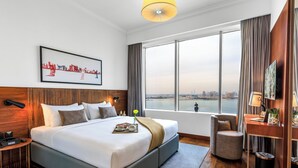 Camera d'albergo con un letto grande, una scrivania, una sedia, una televisione e una finestra con vista sulla città.