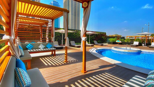 Area piscina sul tetto con pergole in legno, poltrone relax e vasca idromassaggio.