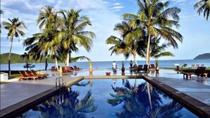 A pool area with palm trees and lounge chairs, overlooking a body of water. - The Frangipani Langkawi Resort & Spa (Langkawi)