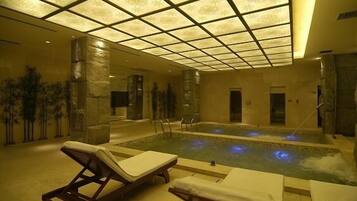 Relax by the serene indoor pool surrounded by lounge chairs and towels.
