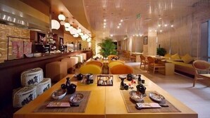 Un restaurante con una larga mesa dispuesta para una comida, rodeada de sillas y una zona de bar.
