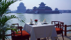 Mesa lista para comer con vista a arquitectura tradicional al otro lado del agua.