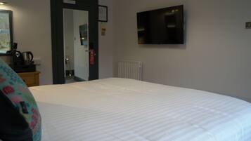 A hotel room with a large bed, a television mounted on the wall, and a radiator.