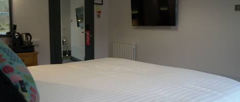 Une chambre d’hôtel avec un grand lit, un téléviseur fixé au mur et un radiateur.
